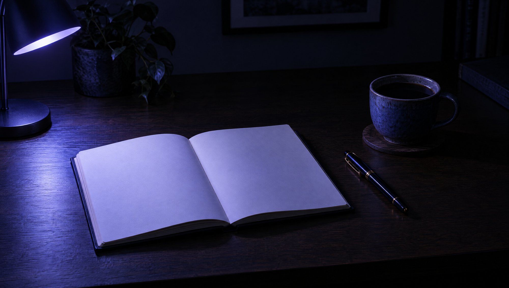 An open notebook with blank pages, a fountain pen and a cup of black coffee on a dark wooden desk, lit by a small lamp casting indigo light.